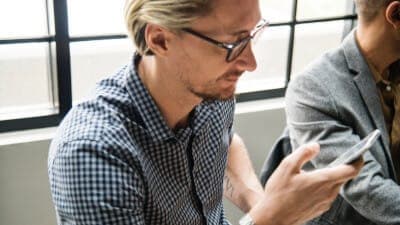 man sitting in a meeting, looking at mobile phone