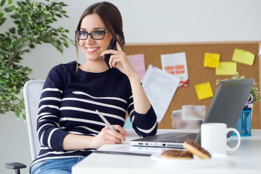 pretty woman wearing glasses sitting at a desk talking on the phone